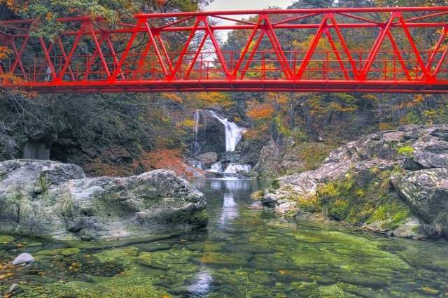 赤い橋を渡り、エメラルドグリーンの滝壺へ【pixta】