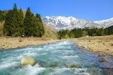 春、残雪の八海山を背景に流れる渓流【pixta】
