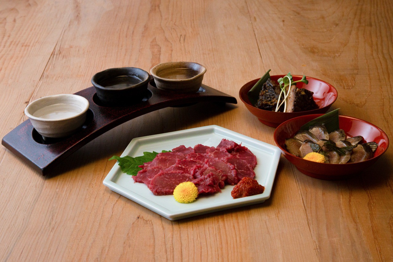 An Aizu local liquors tasting set with Aizu's famous horse sashimi, pepper herring pickles, and small dishes